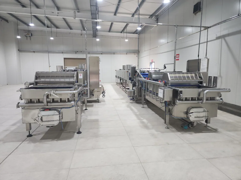 Stainless-steel food-processing lines inside an insulated production room.