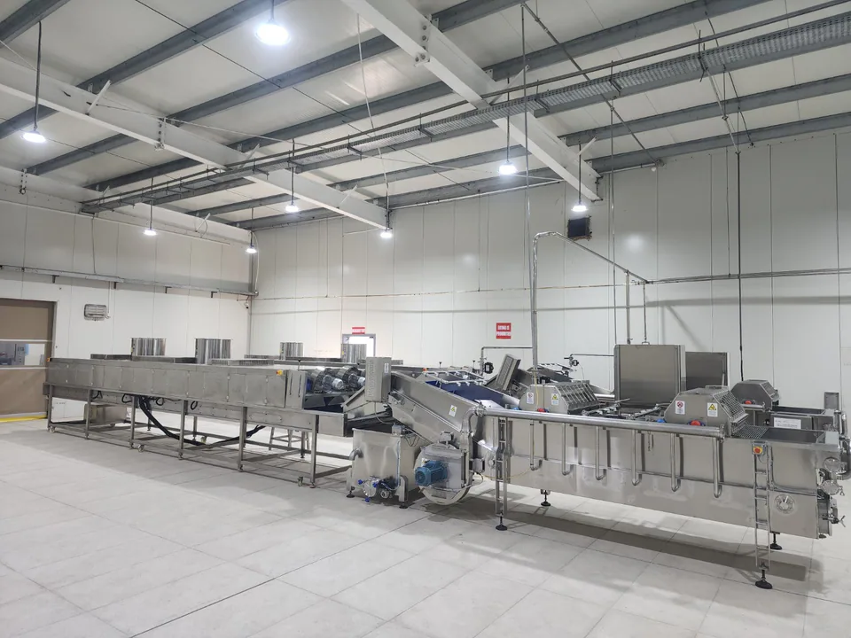 Stainless-steel food-processing line with process equipment inside an insulated production room.